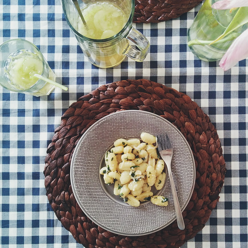 Top view of gnocchi with butter and sage sauce on checkered tablecloth