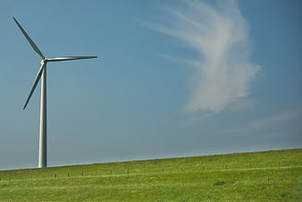 White Wind Turbine in Green Field with Blue Sky