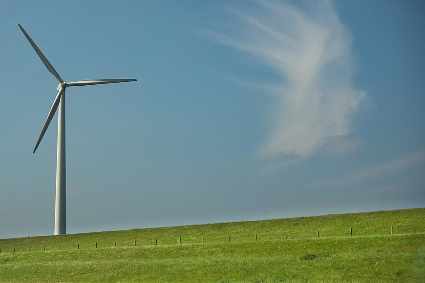 White Wind Turbine in Green Field with Blue Sky