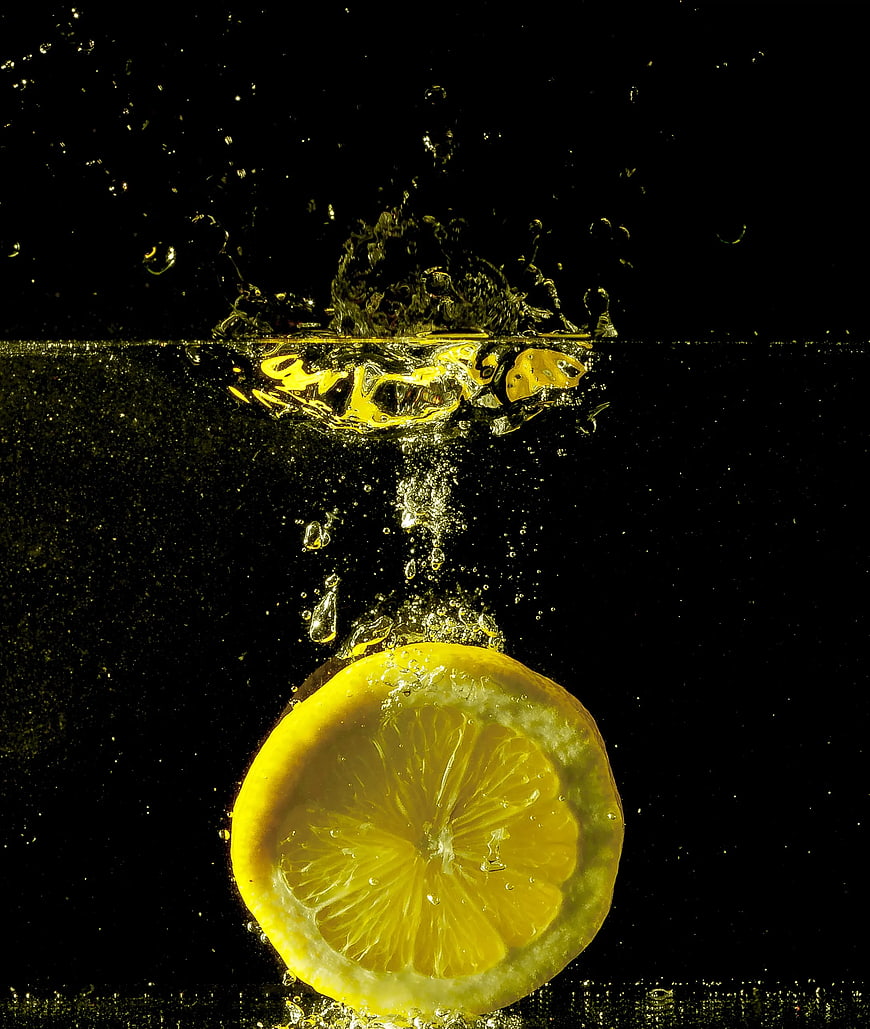 Lemon Slice Splashing into Water on Black Background