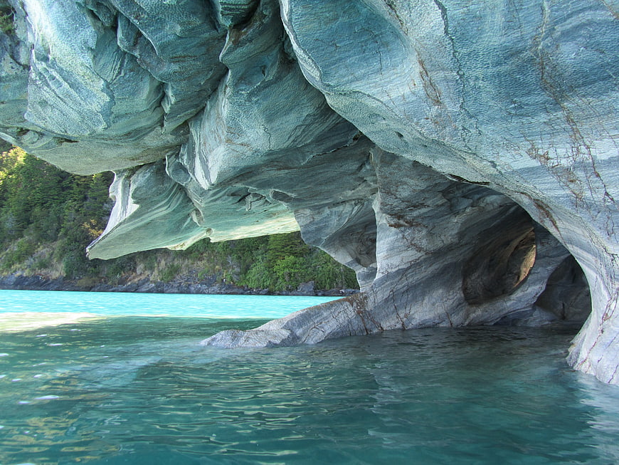 Turquoise water flowing under a massive marble cave formation