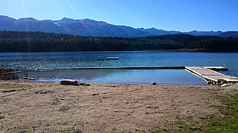 Serene Lake with Wooden Dock and Mountain Backdrop