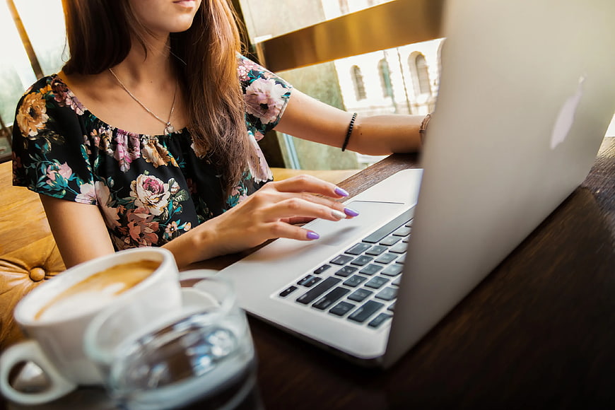 Woman typing on laptop in cafe with coffee