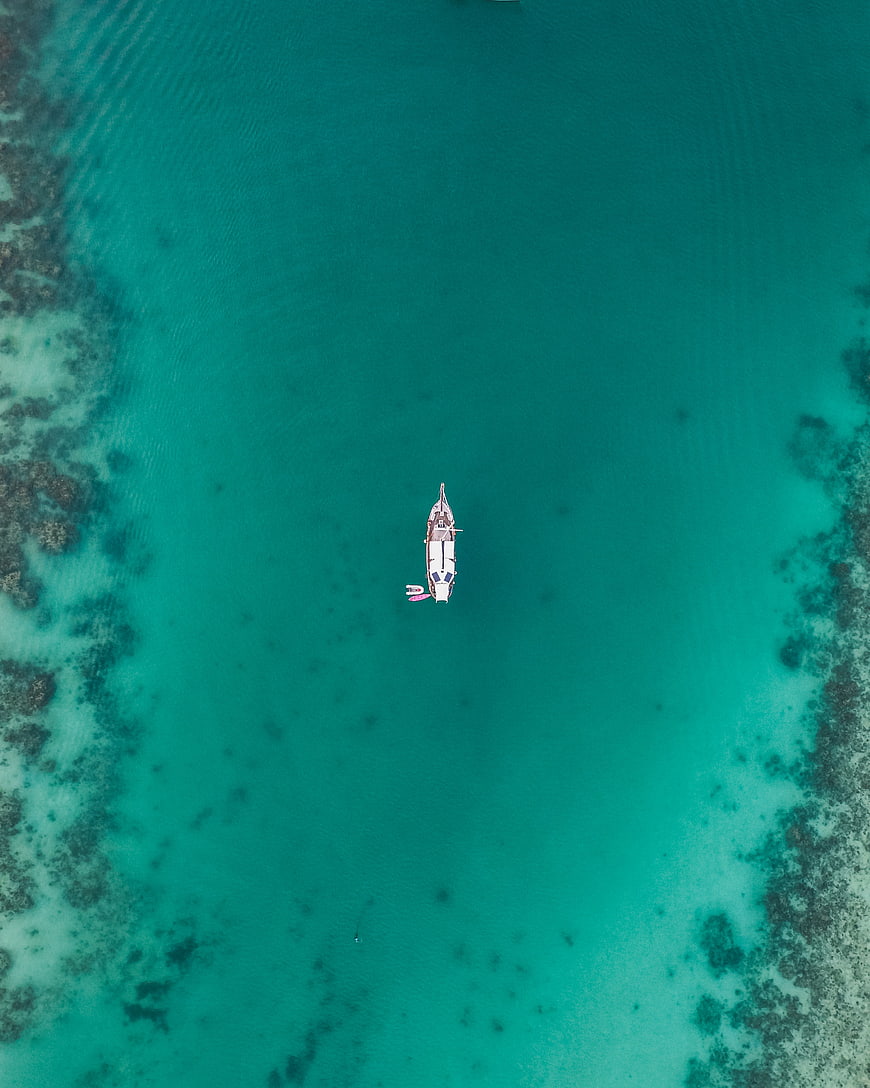 Aerial view of a white boat in turquoise tropical waters