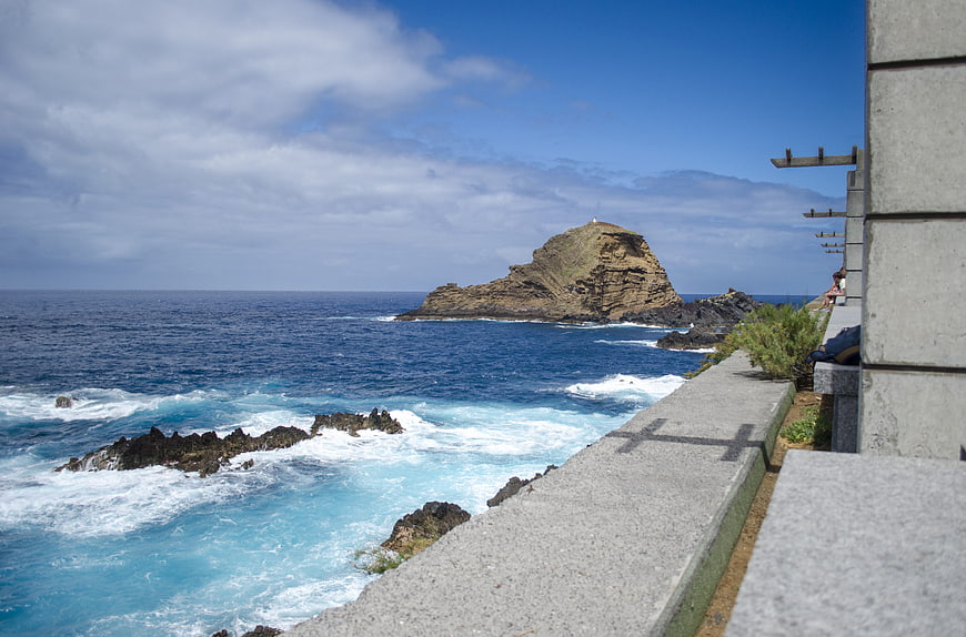 Coastal View of Rocky Island with Turquoise Waves and Concrete Wall