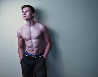 Shirtless Muscular Man Standing Against Plain Wall