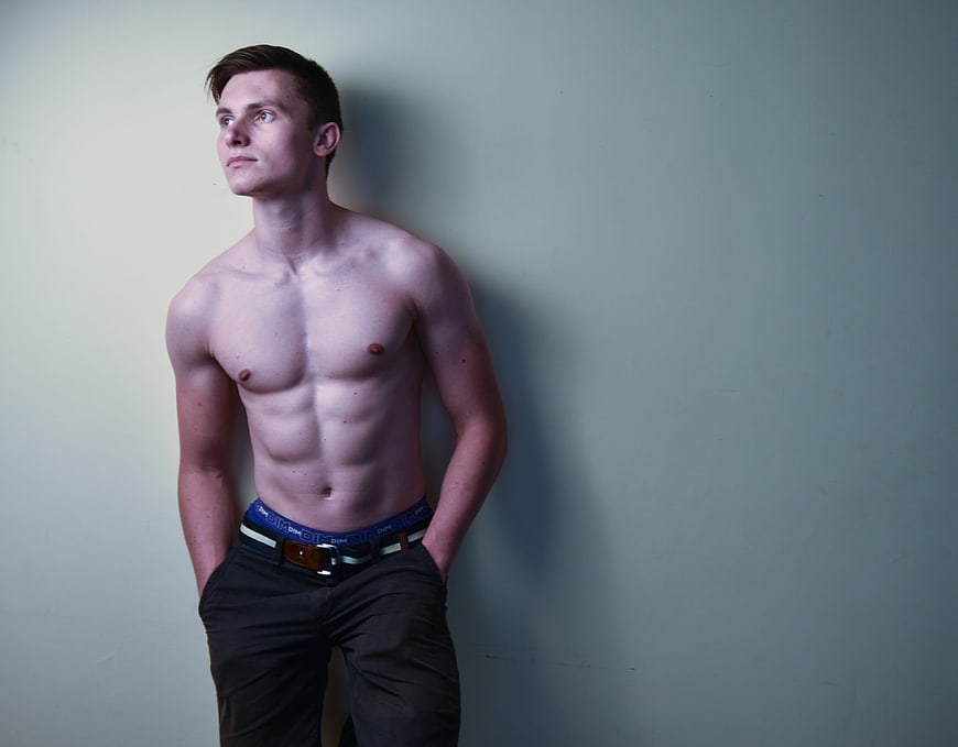 Shirtless Muscular Man Standing Against Plain Wall