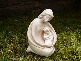 Carved wooden statue of Mary and Jesus on green moss