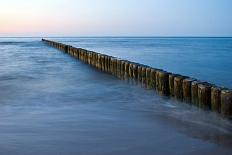 Long Exposure Wooden Groynes in Calm Blue Ocean