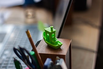Green 3D Printed Toy Boat on Wooden Desk Organizer