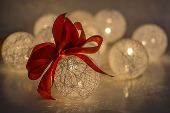 Glowing Christmas Bauble with Red Ribbon and Bokeh Lights