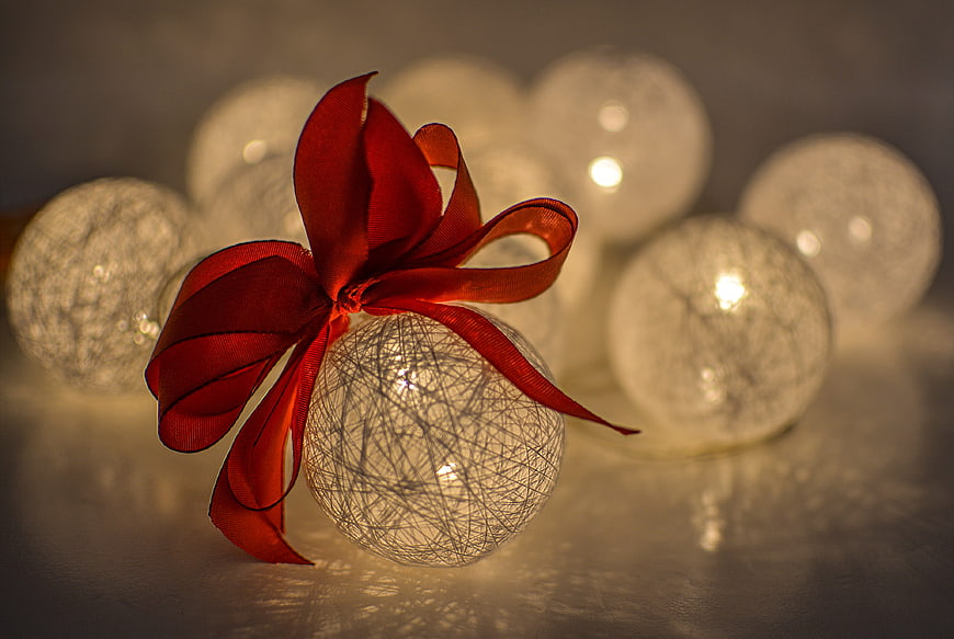 Glowing Christmas Bauble with Red Ribbon and Bokeh Lights