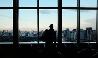Silhouette of Traveler Looking at City Skyline from Window