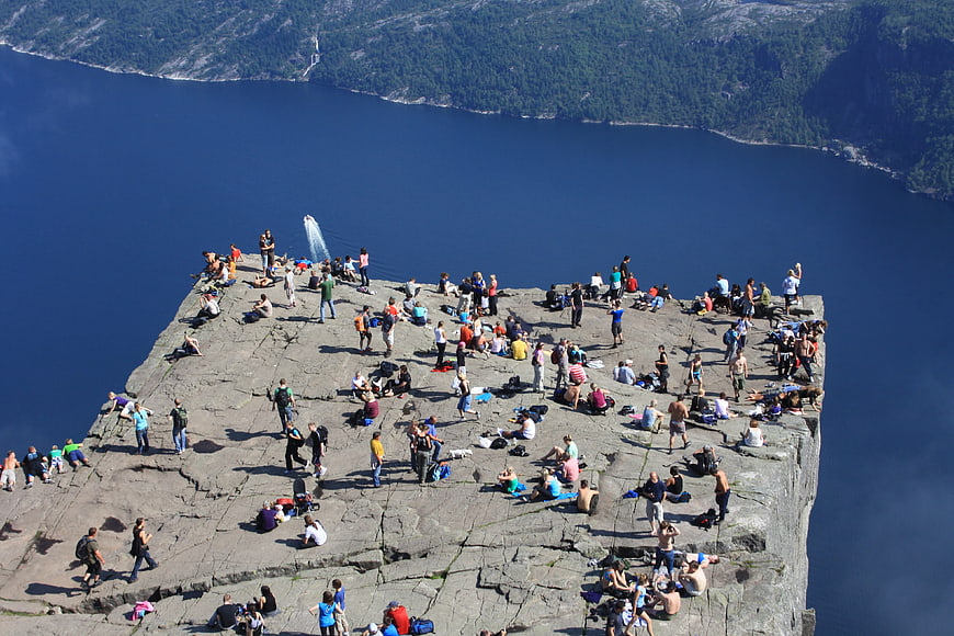 Trolltunga Rock Formation with Hikers Overlooking Fjord