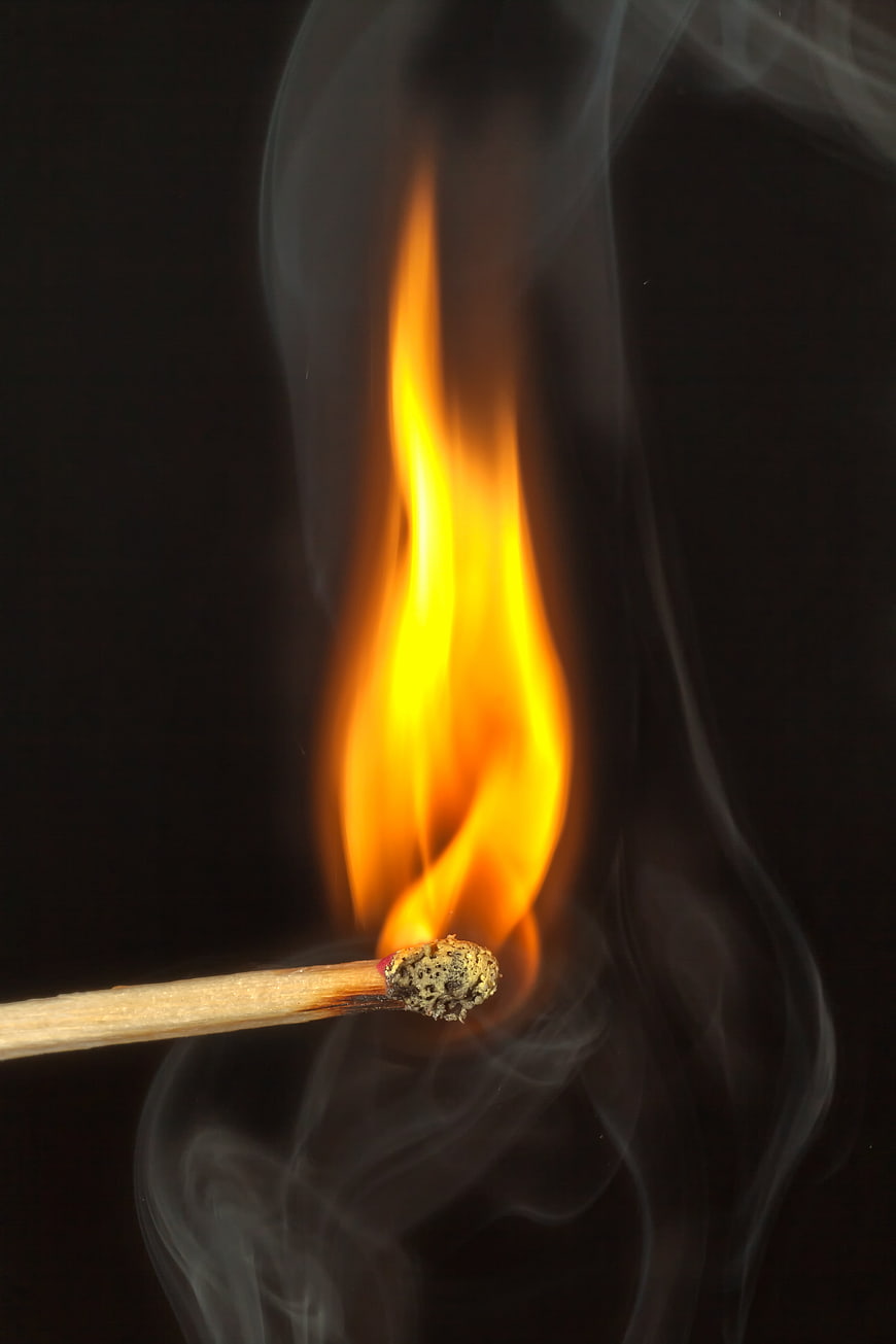 Close-up of burning matchstick with flame and smoke