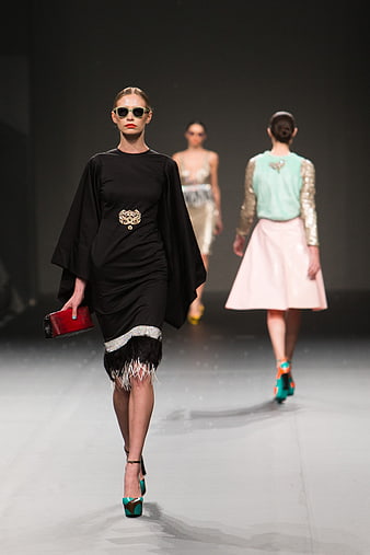 Fashion model walking runway in black dress and sunglasses
