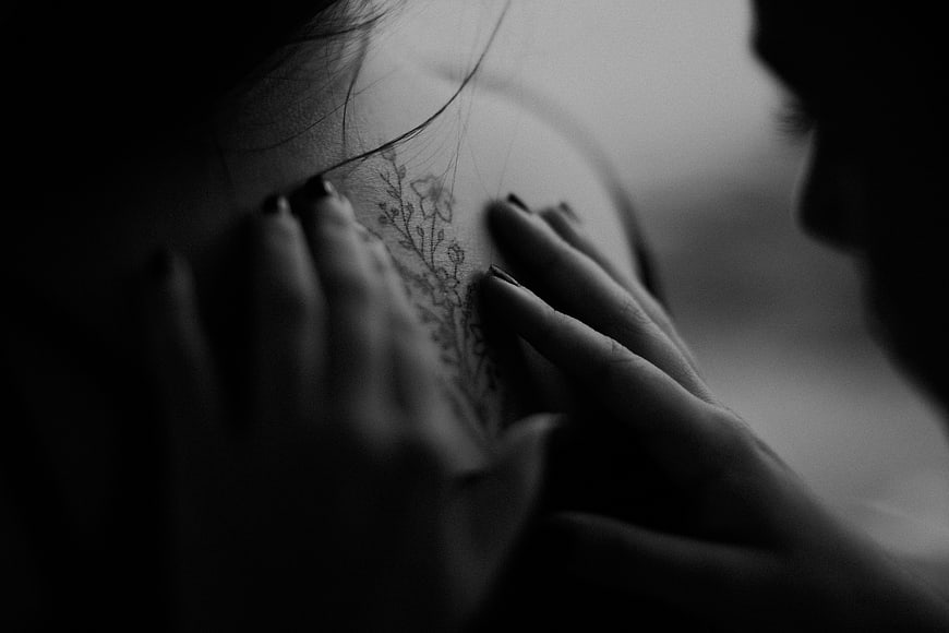 Close-up of hands touching a floral tattoo on skin