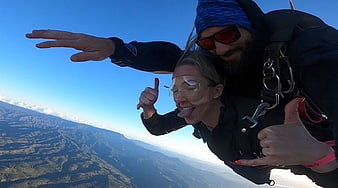 Tandem Skydiving Couple Freefalling Over Mountainous Landscape