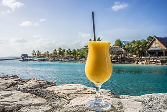 Tropical Yellow Smoothie Drink on Stone Wall by Ocean