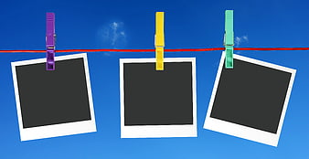 Three empty polaroid frames hanging on a red clothesline against a blue sky