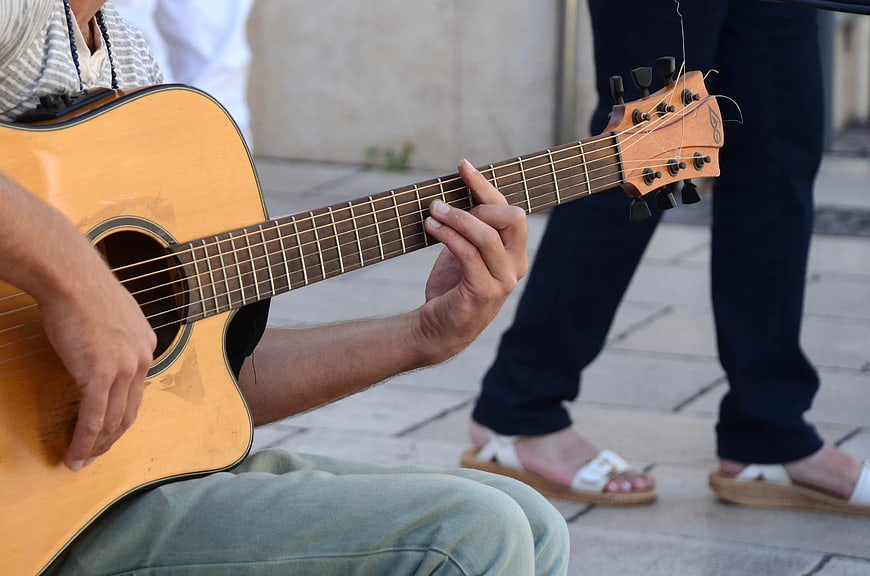 Close-up of hands playing acoustic guitar outdoors