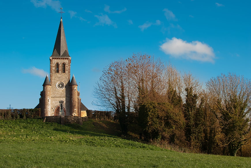 Historic stone church on a grassy hill under blue sky