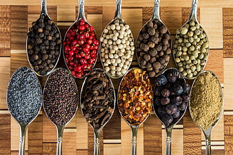 Assorted Spices And Herbs In Silver Spoons On Wooden Board
