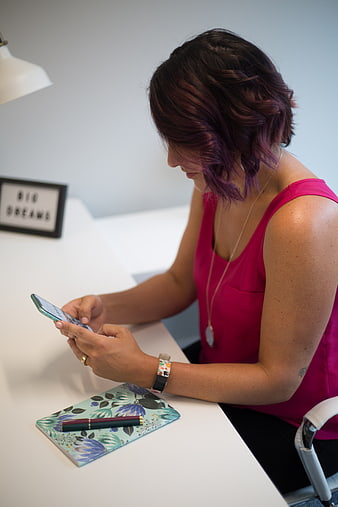 Woman with purple hair using smartphone at white desk
