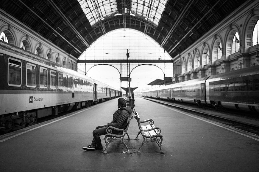 Man Waiting on Bench in Historic Black and White Train Station