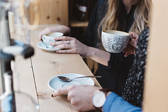 Friends drinking coffee at a wooden cafe counter