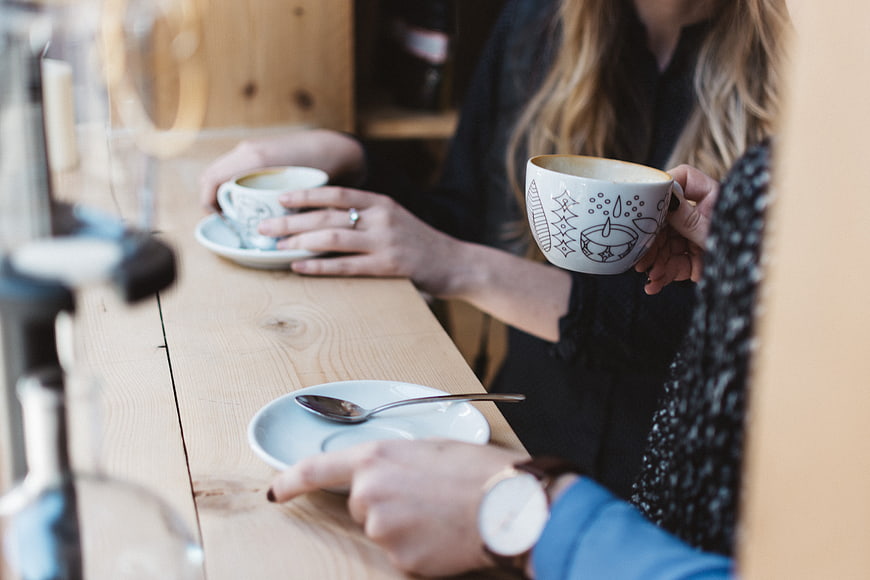 Friends drinking coffee at a wooden cafe counter