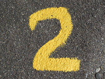 Yellow Number Two Painted On Textured Asphalt Road Surface