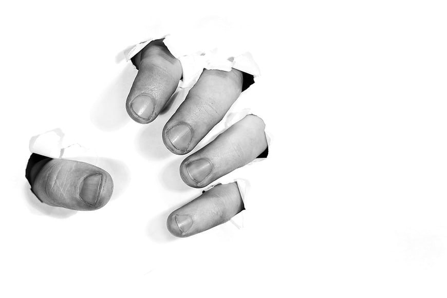Hand tearing through white paper concept of anger and frustration