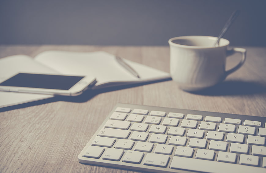 Minimalist Workspace with Keyboard, Coffee, and Notebook
