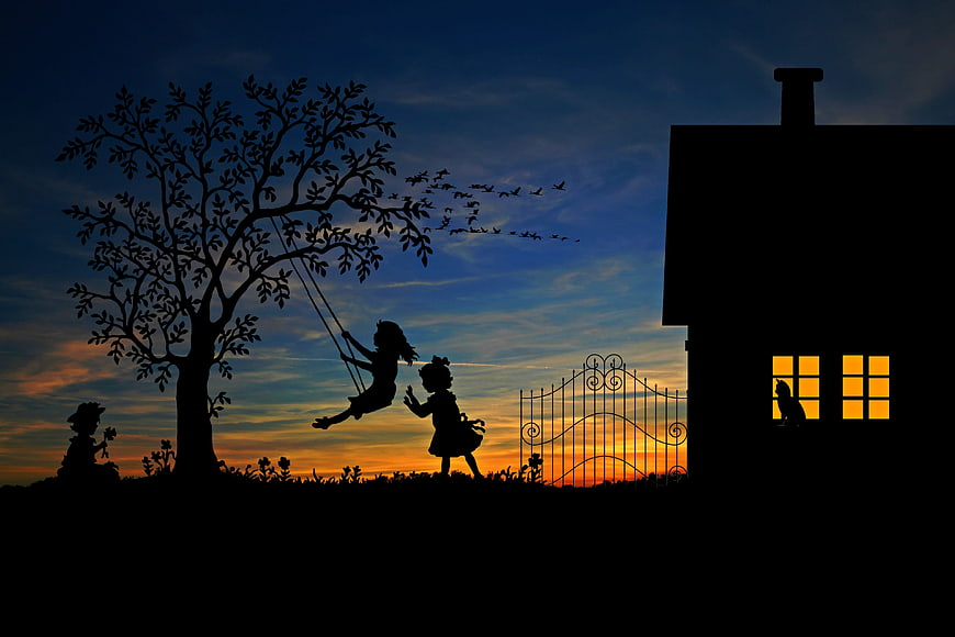 Silhouette of children playing on swing at sunset
