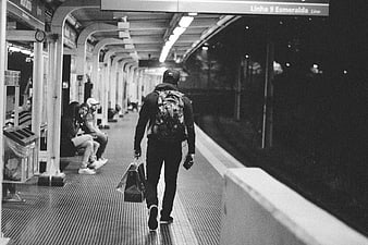 Man with backpack walking on subway platform at night