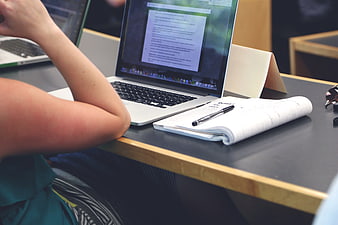 Student working on laptop with notebook and pen
