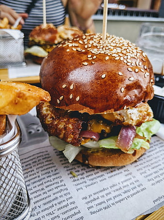 Close-up of Grilled Burger with Fries on Newspaper