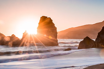 Sunset over coastal rock formation with long exposure waves