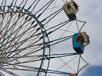 Low angle view of vintage Ferris wheel against cloudy sky