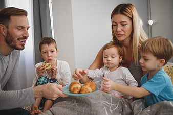 Happy family eating breakfast in bed together