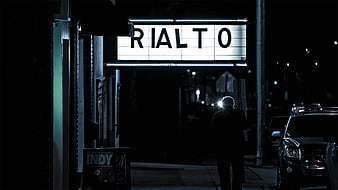 Silhouette of Man Walking Past Rialto Theater Sign at Night