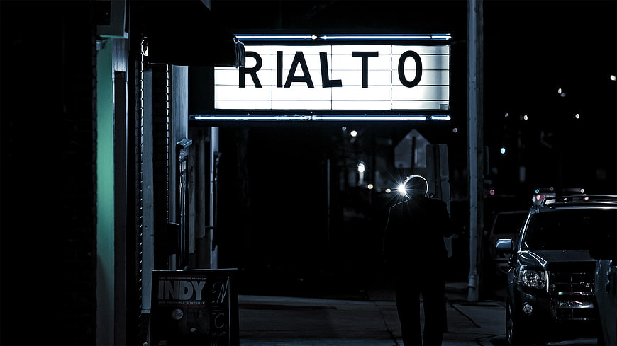 Silhouette of Man Walking Past Rialto Theater Sign at Night
