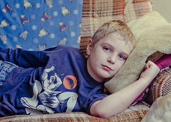 Young boy lying on a couch with a sad and cranky expression