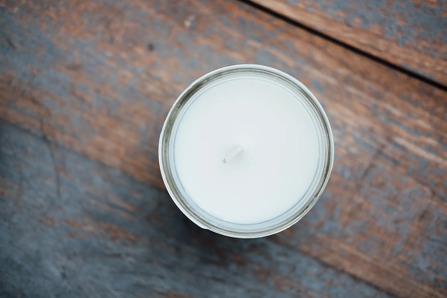 Top View of White Candle in Glass Jar on Wood