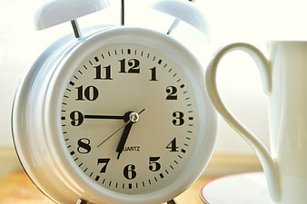 White Alarm Clock And Coffee Cup On Wooden Table