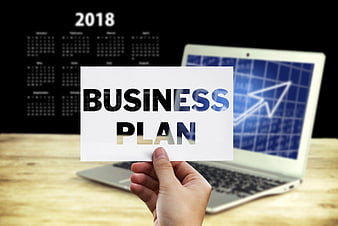 Hand holding business plan card with laptop and calendar