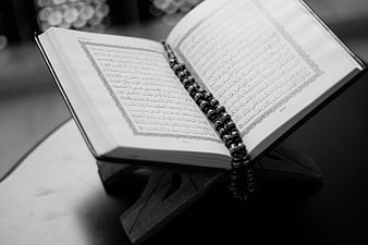 Open Quran with Prayer Beads on Wooden Stand