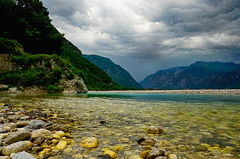 Dramatic river landscape with clear water and stormy mountains