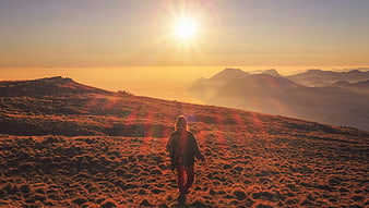 Woman hiking mountain ridge at golden hour sunset